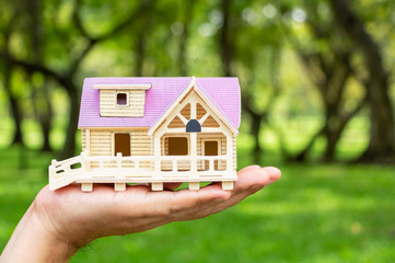 Man holding house model in his hand. The concept of constructing a House, buying, selling.