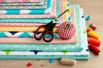 A pile of cotton fabric for sewing. Cotton fabric, scissors, thread and needles for sewing clothes...