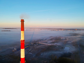Fototapeta premium Aerial view on brick chimney and city covered in fog.