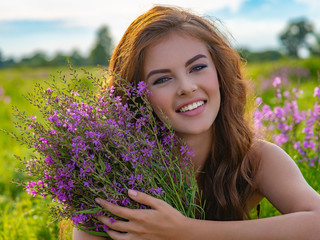Smiling girl in a field with lavender flowers in her hands.