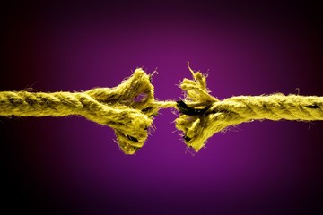 Frayed rope breaking on a dark background