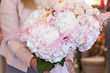 Beautiful bouquet with delicate flowers - roses and hydrangeas. Pink and white bouquet. Bridal bouquet in female hands.