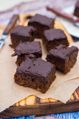 Vegan chocolate sweet brownie cake on wooden kitchen board and parchment paper. Pumpkin, cacao powder, Iranian dates. No bake. Vegetarian raw dessert piece. Paleo diet. Healthy food