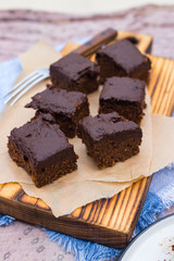 Vegan chocolate sweet brownie cake on wooden kitchen board and parchment paper. Pumpkin, cacao powder, Iranian dates. No bake. Vegetarian raw dessert piece. Paleo diet. Healthy food