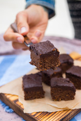 Vegan chocolate sweet brownie cake on wooden kitchen board and parchment paper. Pumpkin, cacao powder, Iranian dates. No bake. Vegetarian raw dessert piece. Paleo diet. Healthy food
