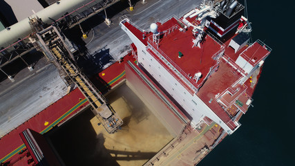 Wide drone shot of ship loading bulk grain in Australian port.