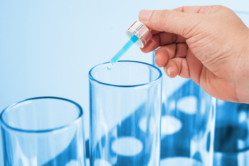 close up hand dropper on test tube on color background.