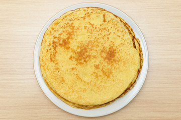 plate of golden baked round pancakes on a wooden table