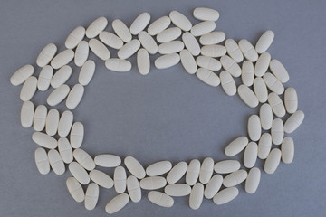 Circle of white medicine tablets or pills on silver color background with copy space for text in middle. Healthcare and medicament addiction concept.