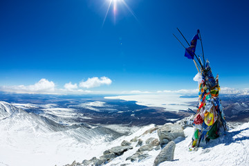 Tibetstkimi post with the flags on the top of a mountain with views of the icy lake