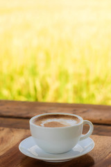 Latte coffee in white cup on wood table with morning light