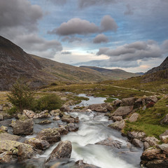 Naklejka na ściany i meble Moody landscape image of river flowing down mountain range near Llyn Ogwen and Llyn Idwal in Snowdonia in Autumn
