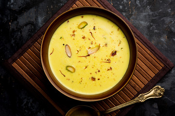Basundi Or Rabri is an Indian sweet popular in Gujarat and Maharashtra. It is a sweetened condensed milk. Garnished with Dry fruits and Saffron. Served in a bowl over moody background. Selective focus