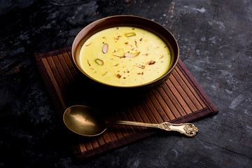 Basundi Or Rabri is an Indian sweet popular in Gujarat and Maharashtra. It is a sweetened condensed milk. Garnished with Dry fruits and Saffron. Served in a bowl over moody background. Selective focus
