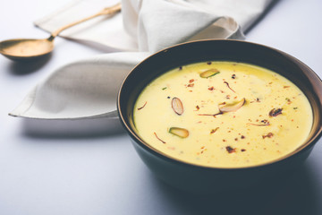 Basundi Or Rabri is an Indian sweet popular in Gujarat and Maharashtra. It is a sweetened condensed milk. Garnished with Dry fruits and Saffron. Served in a bowl over moody background. Selective focus