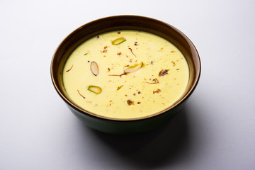Basundi Or Rabri is an Indian sweet popular in Gujarat and Maharashtra. It is a sweetened condensed milk. Garnished with Dry fruits and Saffron. Served in a bowl over moody background. Selective focus