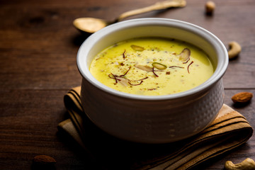 Basundi Or Rabri is an Indian sweet popular in Gujarat and Maharashtra. It is a sweetened condensed milk. Garnished with Dry fruits and Saffron. Served in a bowl over moody background. Selective focus