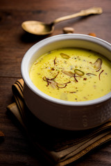 Basundi Or Rabri is an Indian sweet popular in Gujarat and Maharashtra. It is a sweetened condensed milk. Garnished with Dry fruits and Saffron. Served in a bowl over moody background. Selective focus