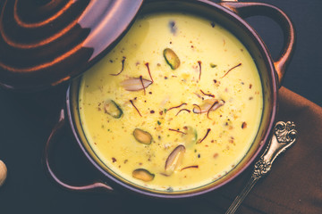 Basundi Or Rabri is an Indian sweet popular in Gujarat and Maharashtra. It is a sweetened condensed milk. Garnished with Dry fruits and Saffron. Served in a bowl over moody background. Selective focus