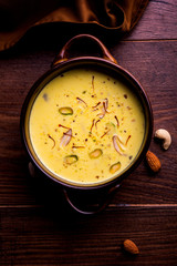 Basundi Or Rabri is an Indian sweet popular in Gujarat and Maharashtra. It is a sweetened condensed milk. Garnished with Dry fruits and Saffron. Served in a bowl over moody background. Selective focus