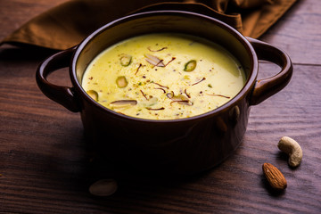 Basundi Or Rabri is an Indian sweet popular in Gujarat and Maharashtra. It is a sweetened condensed milk. Garnished with Dry fruits and Saffron. Served in a bowl over moody background. Selective focus