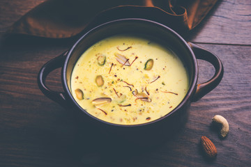 Basundi Or Rabri is an Indian sweet popular in Gujarat and Maharashtra. It is a sweetened condensed milk. Garnished with Dry fruits and Saffron. Served in a bowl over moody background. Selective focus