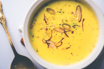 Basundi Or Rabri is an Indian sweet popular in Gujarat and Maharashtra. It is a sweetened condensed milk. Garnished with Dry fruits and Saffron. Served in a bowl over moody background. Selective focus