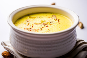 Basundi Or Rabri is an Indian sweet popular in Gujarat and Maharashtra. It is a sweetened condensed milk. Garnished with Dry fruits and Saffron. Served in a bowl over moody background. Selective focus