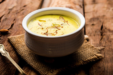 Basundi Or Rabri is an Indian sweet popular in Gujarat and Maharashtra. It is a sweetened condensed milk. Garnished with Dry fruits and Saffron. Served in a bowl over moody background. Selective focus