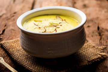 Basundi Or Rabri is an Indian sweet popular in Gujarat and Maharashtra. It is a sweetened condensed milk. Garnished with Dry fruits and Saffron. Served in a bowl over moody background. Selective focus