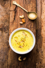 Basundi Or Rabri is an Indian sweet popular in Gujarat and Maharashtra. It is a sweetened condensed milk. Garnished with Dry fruits and Saffron. Served in a bowl over moody background. Selective focus