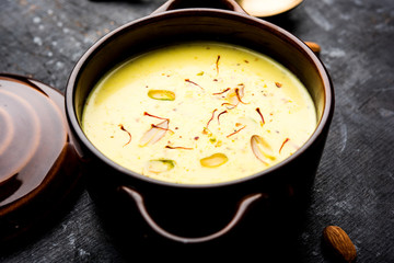 Basundi Or Rabri is an Indian sweet popular in Gujarat and Maharashtra. It is a sweetened condensed milk. Garnished with Dry fruits and Saffron. Served in a bowl over moody background. Selective focus