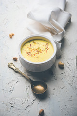 Basundi Or Rabri is an Indian sweet popular in Gujarat and Maharashtra. It is a sweetened condensed milk. Garnished with Dry fruits and Saffron. Served in a bowl over moody background. Selective focus