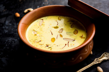 Basundi Or Rabri is an Indian sweet popular in Gujarat and Maharashtra. It is a sweetened condensed milk. Garnished with Dry fruits and Saffron. Served in a bowl over moody background. Selective focus