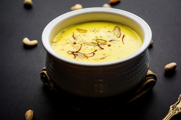 Basundi Or Rabri is an Indian sweet popular in Gujarat and Maharashtra. It is a sweetened condensed milk. Garnished with Dry fruits and Saffron. Served in a bowl over moody background. Selective focus