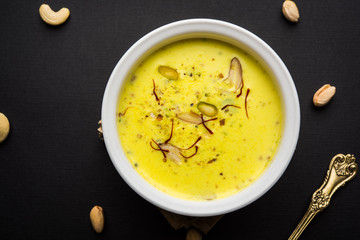 Basundi Or Rabri is an Indian sweet popular in Gujarat and Maharashtra. It is a sweetened condensed milk. Garnished with Dry fruits and Saffron. Served in a bowl over moody background. Selective focus