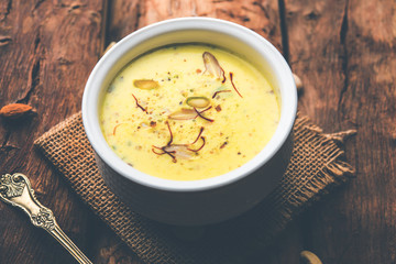 Basundi Or Rabri is an Indian sweet popular in Gujarat and Maharashtra. It is a sweetened condensed milk. Garnished with Dry fruits and Saffron. Served in a bowl over moody background. Selective focus