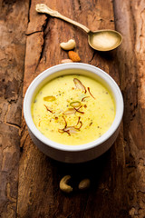 Basundi Or Rabri is an Indian sweet popular in Gujarat and Maharashtra. It is a sweetened condensed milk. Garnished with Dry fruits and Saffron. Served in a bowl over moody background. Selective focus