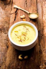 Basundi Or Rabri is an Indian sweet popular in Gujarat and Maharashtra. It is a sweetened condensed milk. Garnished with Dry fruits and Saffron. Served in a bowl over moody background. Selective focus