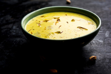 Basundi Or Rabri is an Indian sweet popular in Gujarat and Maharashtra. It is a sweetened condensed milk. Garnished with Dry fruits and Saffron. Served in a bowl over moody background. Selective focus