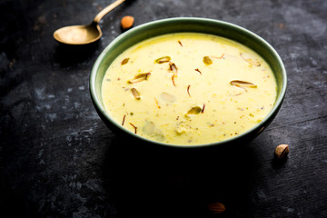 Basundi Or Rabri is an Indian sweet popular in Gujarat and Maharashtra. It is a sweetened condensed milk. Garnished with Dry fruits and Saffron. Served in a bowl over moody background. Selective focus