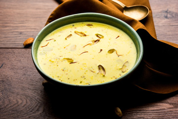 Basundi Or Rabri is an Indian sweet popular in Gujarat and Maharashtra. It is a sweetened condensed milk. Garnished with Dry fruits and Saffron. Served in a bowl over moody background. Selective focus