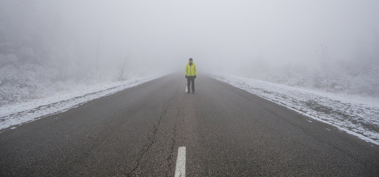 mysterious man walking in the mist by road