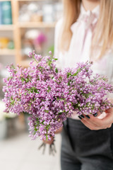 Sunny spring morning. Young happy woman holding a beautiful bunch of lilac. Present for a smiles girl.