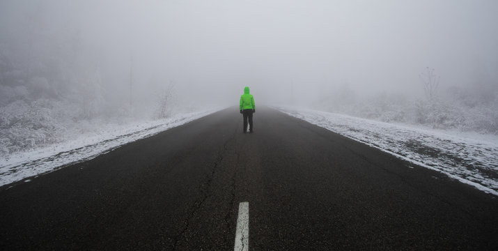 mysterious man walking in the mist by winter road