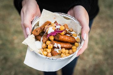 Traditional gourmet Basque Spanish chistorra chorizo sausage with chickpeas, marinated red onion, and yoghurt sauce at a street food market fair festival