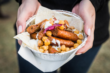 Traditional gourmet Basque Spanish chistorra chorizo sausage with chickpeas, marinated red onion, and yoghurt sauce at a street food market fair festival