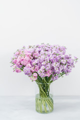 Bouquet of Beautiful lilac color gillyflower, levkoy or matthiola. Spring flowers in vase on wooden table. Vertical photo
