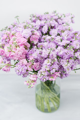 Naklejka na ściany i meble Bouquet of Beautiful lilac color gillyflower, levkoy or matthiola. Spring flowers in vase on wooden table. Vertical photo