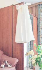 .Vertical photography. Preparations for the wedding. Morning bride. The dress hangs on the wardrobe, shoes are on the couch in a beautiful room.